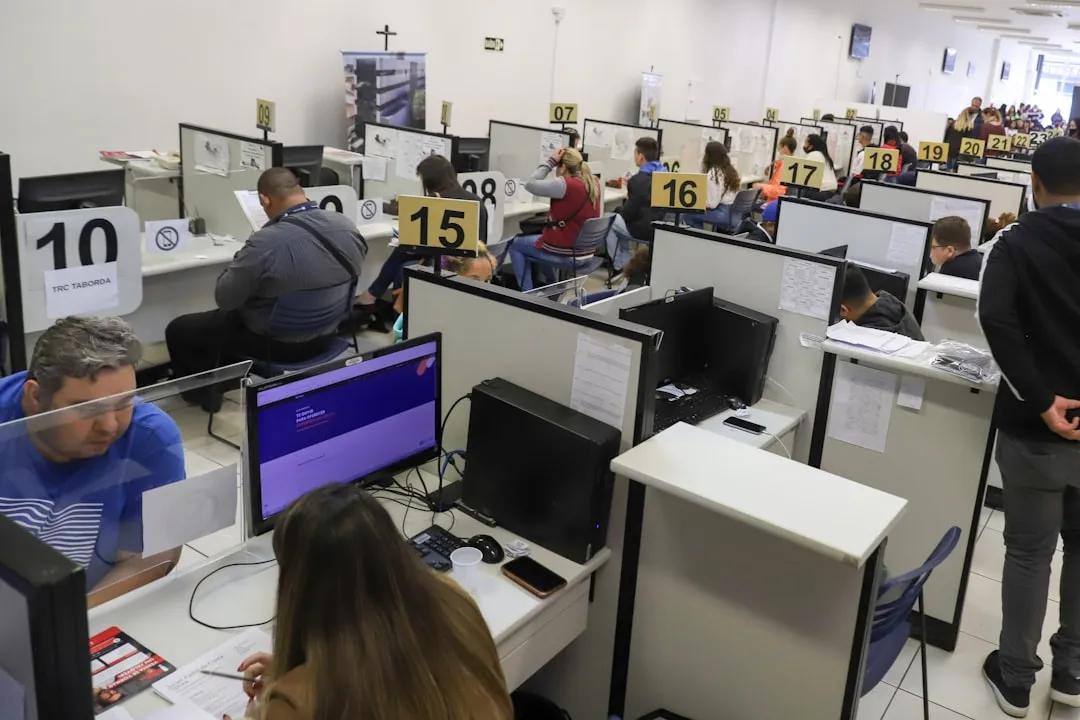 Person typing on a laptop with a blurred screen showing job listings in a modern office; no readable text