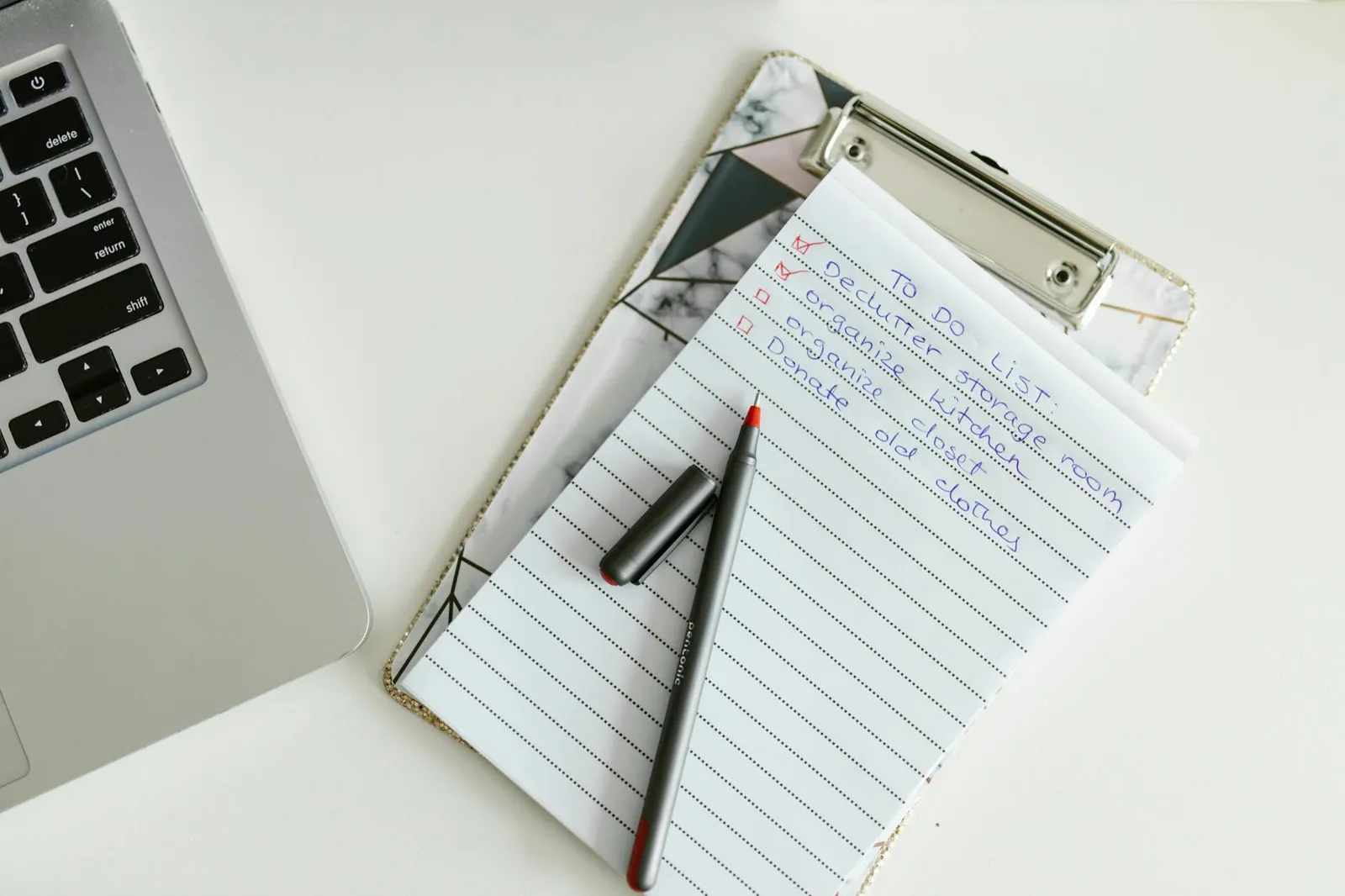 Laptop and a paper checklist with empty boxes, organized workspace, no readable text